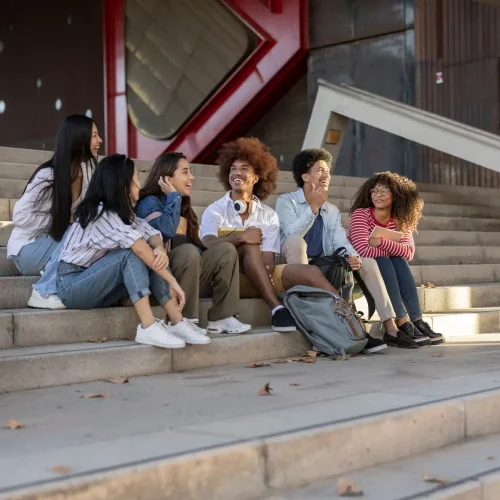 group-of-multiracial-students-talking-and-sitting-on-the-stairs-of-the-university-