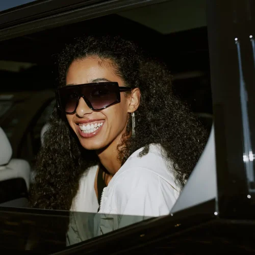 portrait-of-smiling-female-celebrity-in-sunglasses-sitting-in-car
